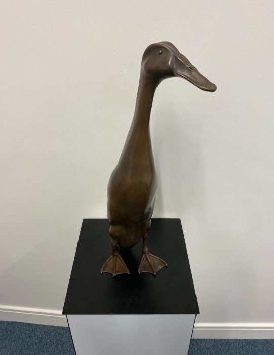 Final bronze statue of Long Boi, on a black surface.