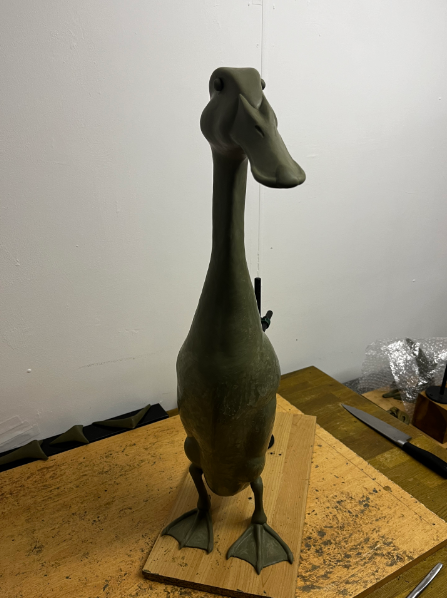 Unfinished Long Boi statue on wooden work surface.