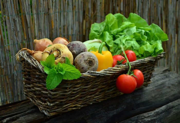 An assortment of brightly coloured vegetables in a brown woven basket.