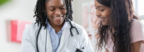 Female doctor talking to young female patient and smiling