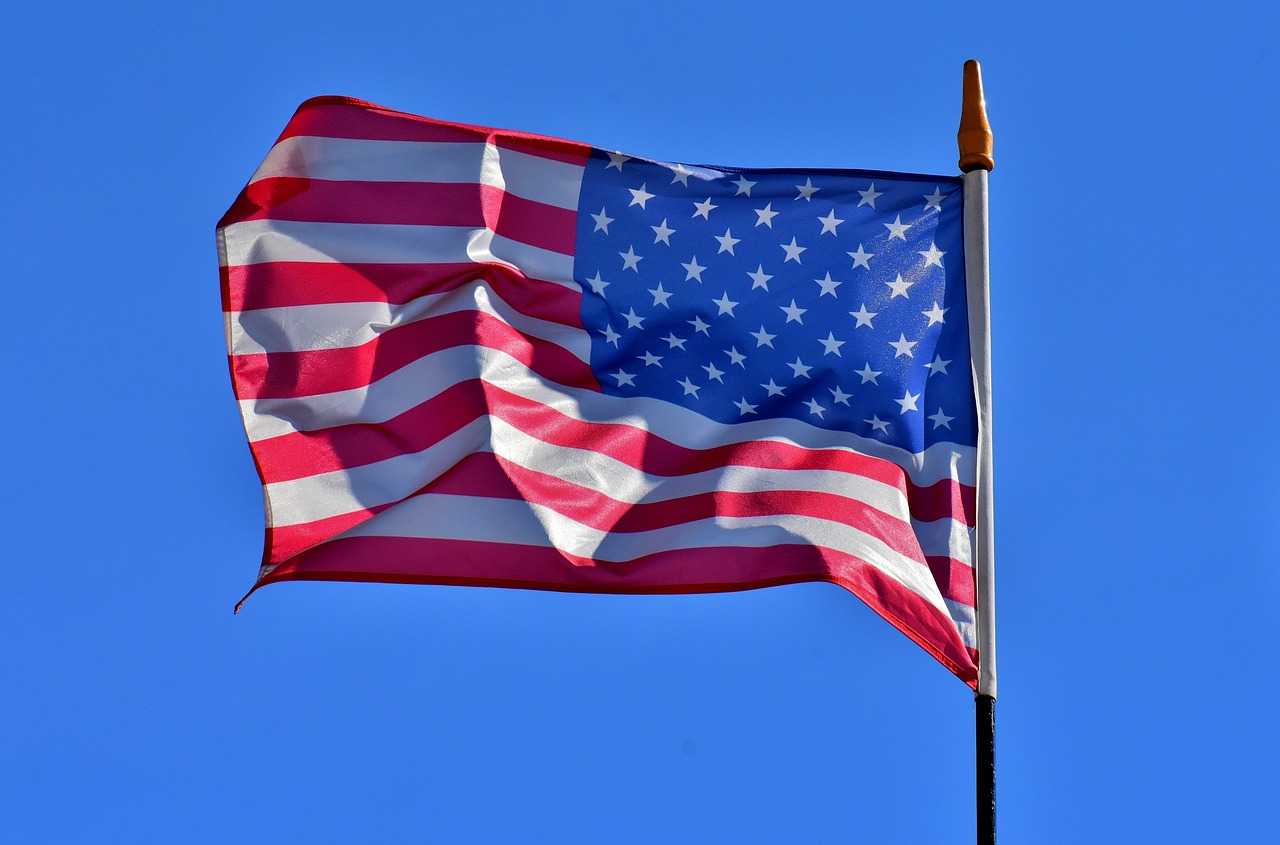 An American flag blowing in the wind against the backdrop of a blue sky