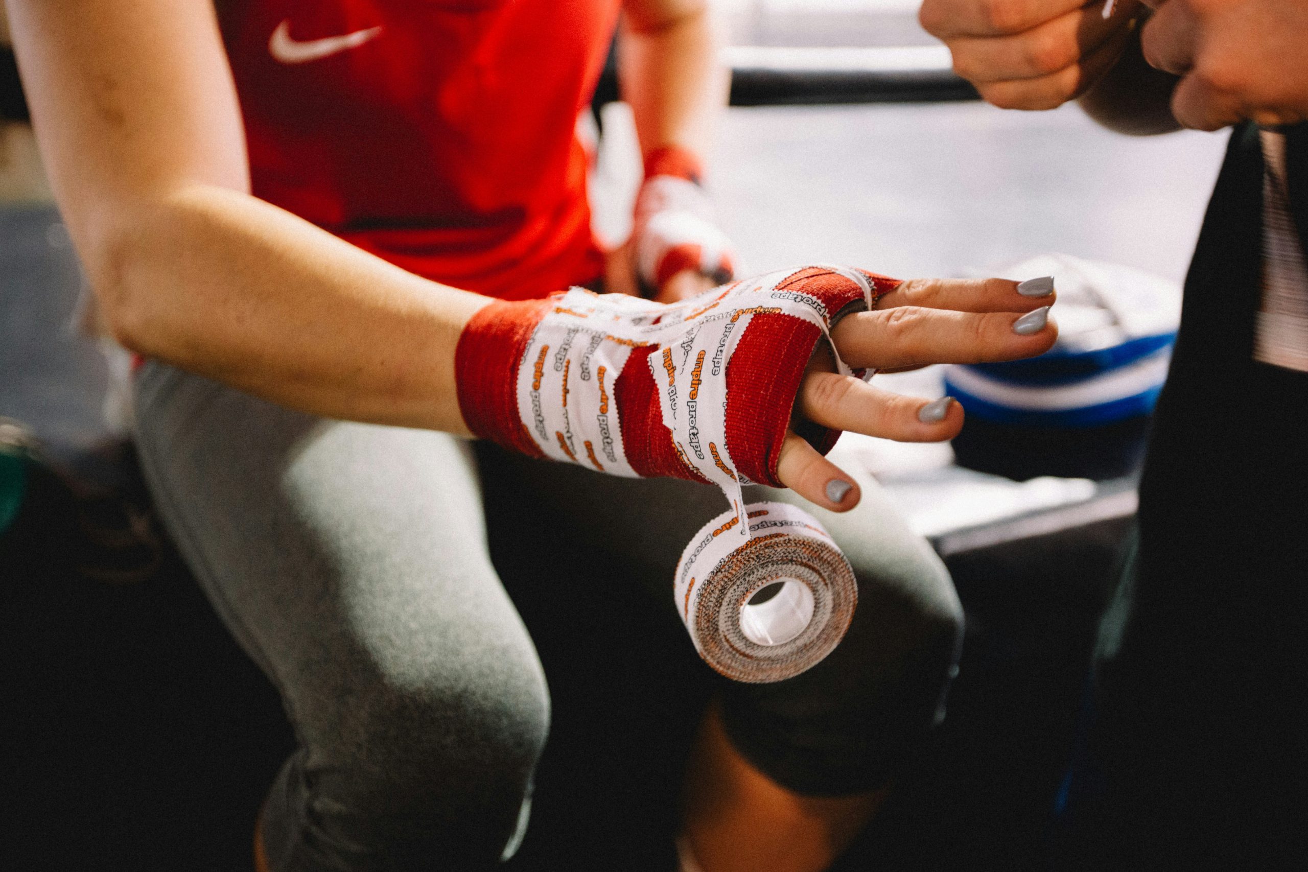 Hand being wrapped with red boxing tape.