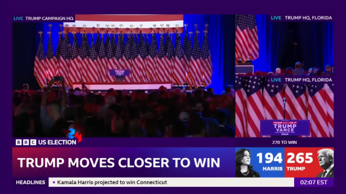 A screenshot of the BBC's election night coverage. The background is purple, with three different cameras on an empty stage at Donald Trump's victory party. The lower thirds also have a purple theme.