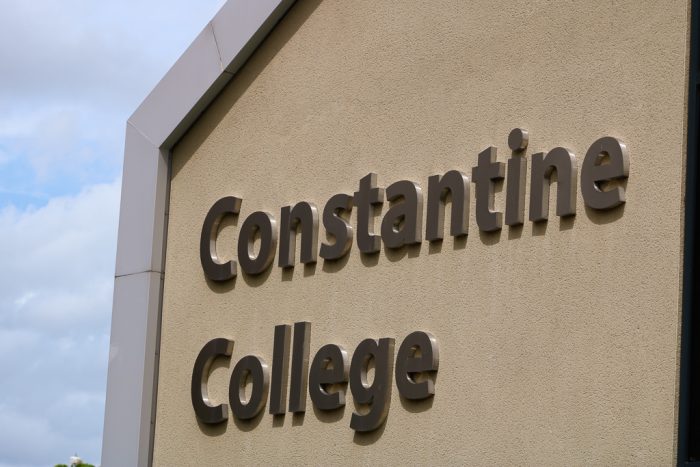 Constantine College Sign Letters on beige wall background