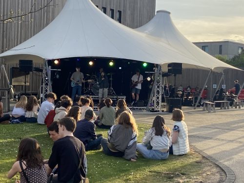 people sat on grass watching a band