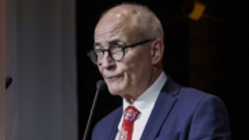 A man in a red tie gives a speech