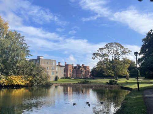 Heslington Hall behind a lake with blue skies